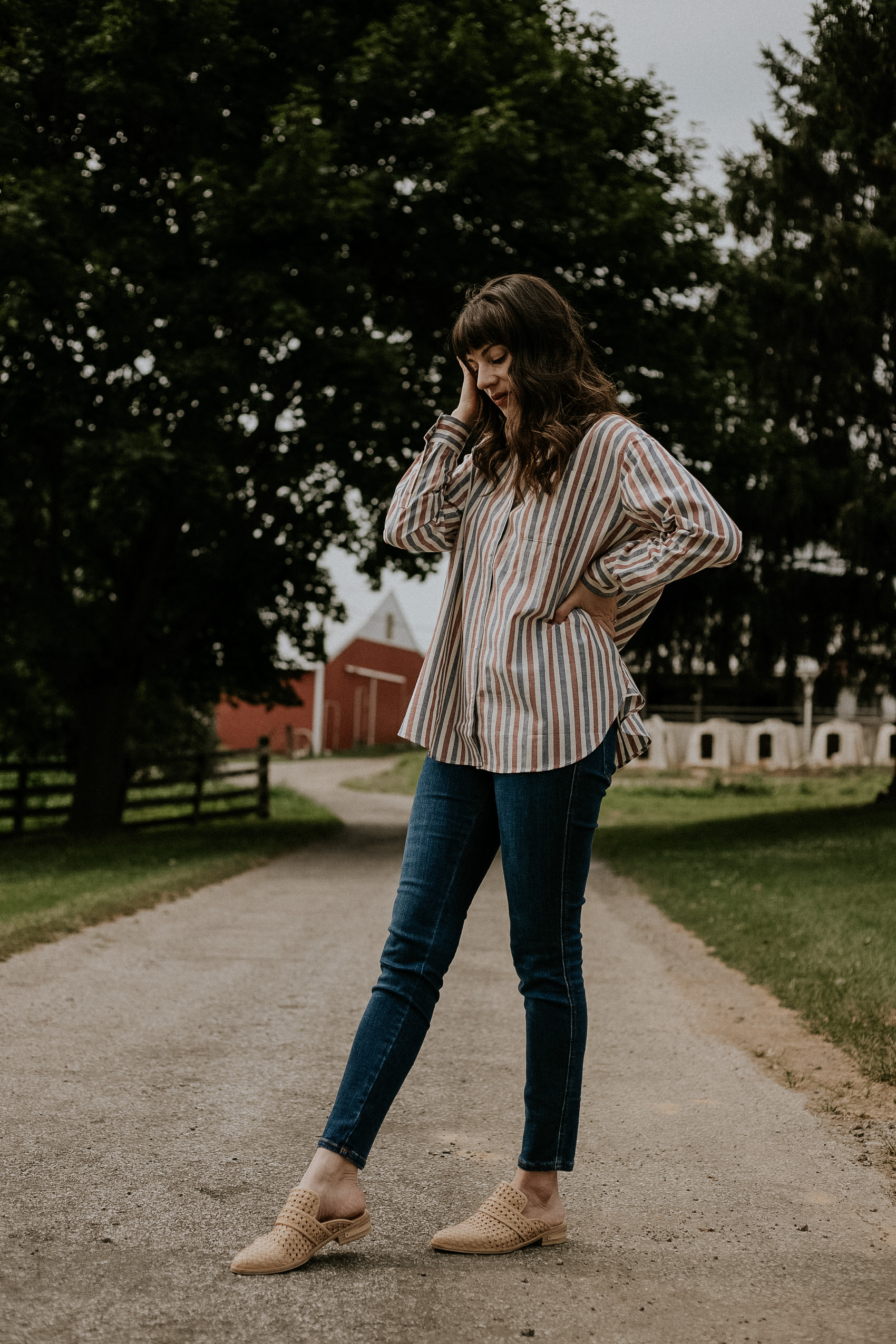 An oversized striped button down shirt with skinny jeans and woven mules